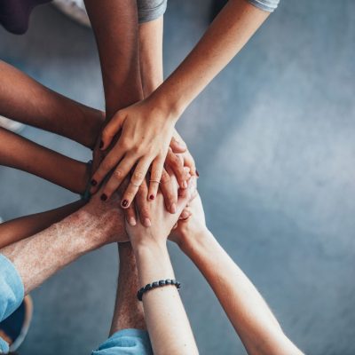 Close up top view of young people putting their hands together. Friends with stack of hands showing unity.